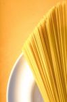 Raw Spaghetti  On The White Plate On The Yellow Background Vertical Stock Photo