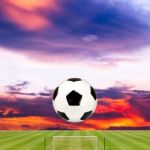 Soccer Ball With Soccer Field Against Beautiful Sunset Stock Photo