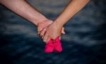 Young Couple Holding Baby Shoes Stock Photo