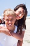 Girl Riding On Guy At Beach Stock Photo