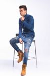 Male Model In Denim Jeans Sitting On A Chair . Studio Shoot Stock Photo