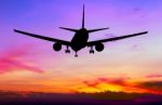 Silhouetted Commercial Airplane Flying At Sunset Stock Photo