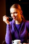 Young Woman Holding A Spoon And Drinking Cappuccino Stock Photo