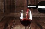 Red Wine Is Poured From Bottle To Glass Stock Photo