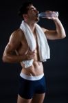 Beautiful And Muscular Man Drinking Water In Dark Background Stock Photo