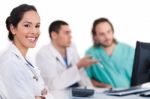 Smiling Young Doctor With Other Doctors Behind Her Stock Photo