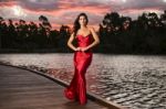 Beautiful Young Woman In The Gardens Wearing A Long Silk Red Dress Stock Photo