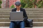 Student Working On His Laptop With An Irish Cap Stock Photo