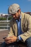 Middle-aged Man With Irish Beret Looking At His Smartphone Stock Photo