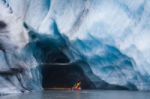 Kayaking Into Blue Ice Cave Stock Photo