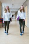 Two Dutch Teenage Girls Walking In Long School Corridor Carrying Stock Photo