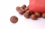 Roasted Chestnuts Outside Red Bag On White Floor Stock Photo