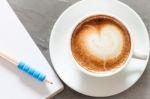 Coffee Cup With Notepad On Grey Background Stock Photo