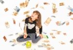 Little Girl Saving Money In Piggy Bank With Money Bills Flying Everywhere Around Stock Photo