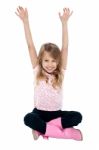 Young Girl Seated On Floor Posing With Raised Arms Stock Photo