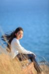 Portrait Of Asian Girl Relaxing Emotion Sitting In Grass Field And Windy Evening Use For Teen Age Leisure And Activities Traveling Vacation Time Stock Photo