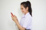 Portrait Of Thai High School Student Uniform Teen Beautiful Girl Using Her Phone And Smile Stock Photo