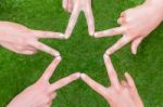 Hands Of Girls Making Star Shape Above Grass Stock Photo