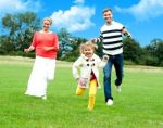 Happy Family Running In Park Stock Photo