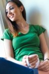 Beautiful Brunette Girl Who Is Sitting On The Floor And Drinking Stock Photo