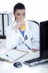 Doctor Drinking A Glass Of Juice At Her Workplace Stock Photo