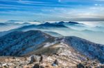 Professional Photographer Takes Photos With Camera On Tripod On Rocky Peak At Sunset Stock Photo