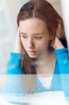 Depressed Young Woman Sitting At Home Stock Photo