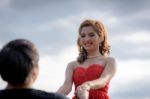 Young Woman In Red Dress Is Holding Hands With Young Man Stock Photo