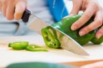 Woman Hand Cutting A Green Pepper In Kitchen Stock Photo