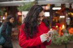 Woman In Red Coat Read Good News On Smartphone In Hands, Urban S Stock Photo