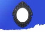 Oval Black Picture Frame With A Decorative On Blue Wall Stock Photo