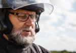 Elderly Motorcyclist Wearing A Jacket And Glasses With A Helmet Stock Photo