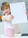 Child Drawing With Crayons, Sitting At Table In Kitchen At Home Stock Photo