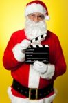 Cheerful Kris Kringle Posing With Clapperboard Stock Photo