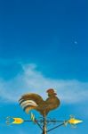 A Cockerel Wind Vane Against Blue Sky Stock Photo