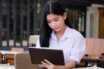 Portrait Of Thai High School Student Uniform Beautiful Girl Using Her Tablet Stock Photo