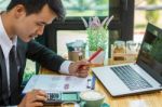 Business Man Sitting On A Calculator To Figure Out In A Coffee S Stock Photo