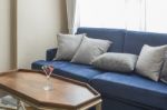 Luxury Blue Sofa With Grey Pillows And Wooden Table Stock Photo