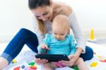 Mother And Baby Girl Using Digital Tablet At Home Stock Photo