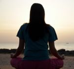 Young Woman Meditating On Beach Stock Photo