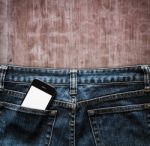 Blue Jeans With Cell Phone In A Pocket Background Stock Photo