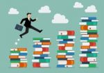 Businessman Jumping Over Higher Stack Of Books Stock Photo