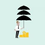 Businessman With The Beard Holding An Open Umbrella Over Golden Coins Stock Photo