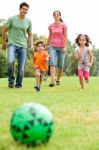 Family Playing Football In The Park Stock Photo