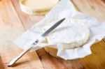 Camembert Cheese Wrapped In Paper With Vintage Knife On Wooden T Stock Photo