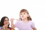 Girl Blowing Soap Bubbles With Mom Stock Photo