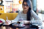 Young Beautiful Woman Using Her Mobile Phone In Coffee Stock Photo