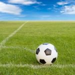 Soccer Ball On Soccer Field Against Blue Sky Stock Photo