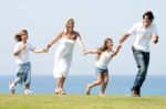 Family Running On Meadow Stock Photo