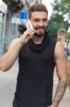 Man With A Beard Talking With Your Smart Phone On The Street Stock Photo